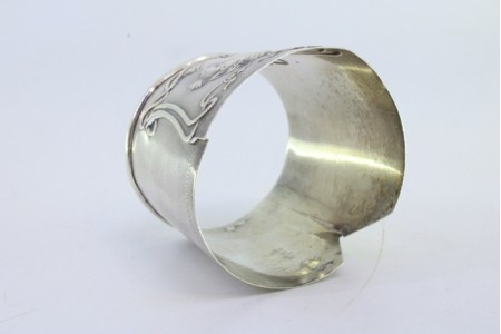 Argola de guardanapo em prata em forma de punho e relevada com motivos florais e busto de dama.